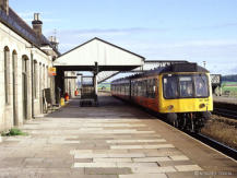 A Derby Heavyweight in SPTE orange and black livery waits for early morning commuters at Inverurie,